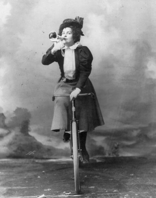 Black and white photo of woman on an old bike with a horn
